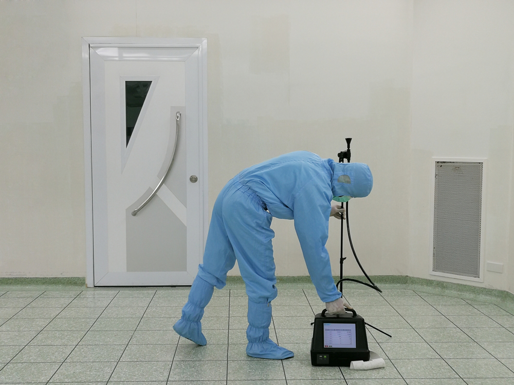 Inspector using particle counter to test dust inside cleanroom