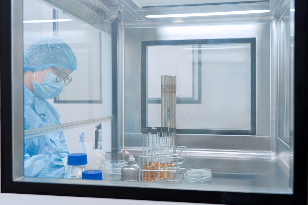 Microbiologist testing sample in laminar air flow cabinet in clean room 