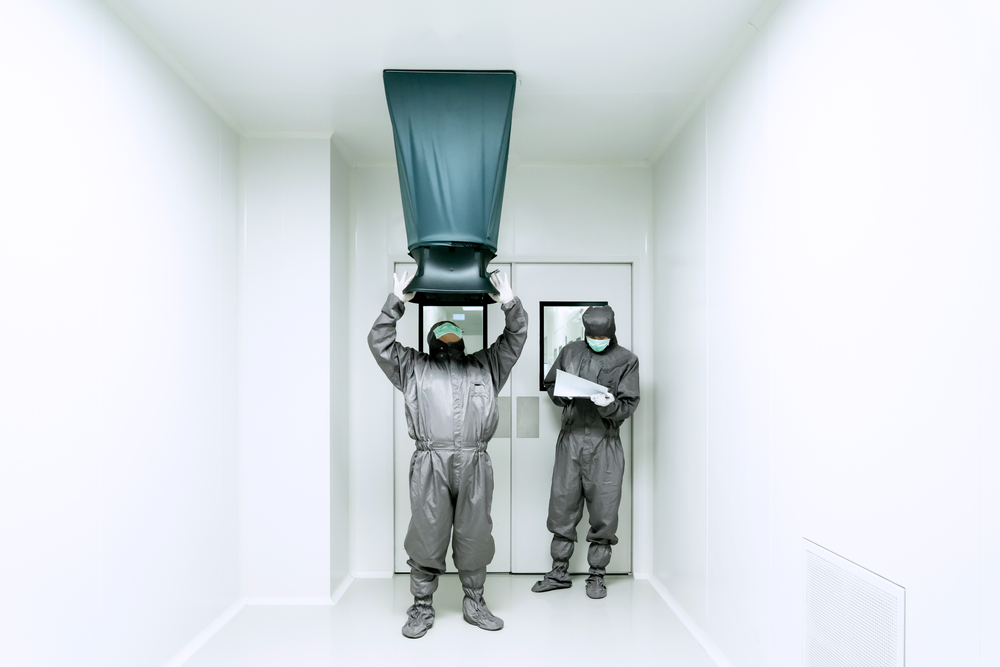 Operators measuring the air velocity and volume of supply air from HVAC system in cleanroom.