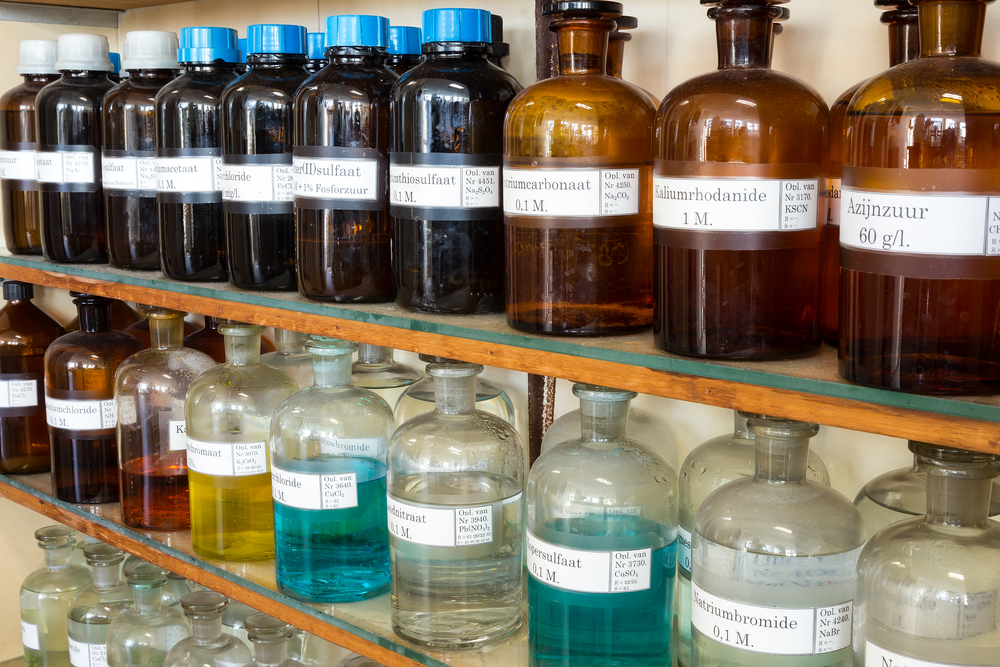 Rows of chemicals in glass bottles on shelves at chemistry on secondary school