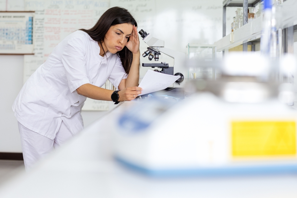 Tired scientist standing at fixed-height lab bench